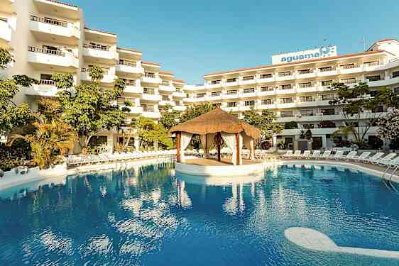 Hotellikompleksi, jossa useita kerroksia, suuri uima-allas ja katkokatosrakennelma altaan keskellä. (Tekoälyn luoma teksti)