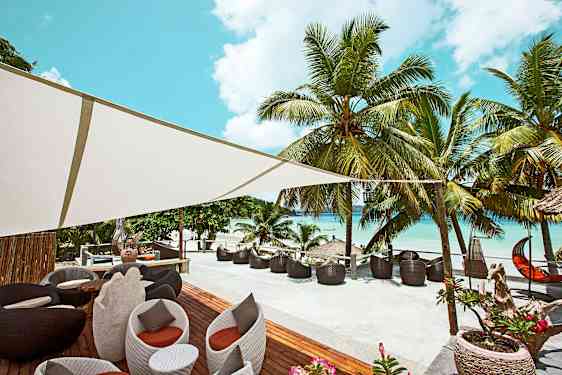 Ulkotila, jossa istuimia ja palmuja rannan vierellä. (Tekoälyn luoma teksti)