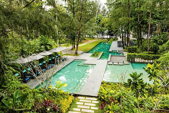 Trooppinen ulkouima-allas, jossa on aurinkotuoleja ja vehreitä ympäristöjä. (Tekoälyn luoma teksti)