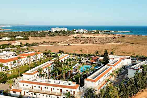 Lentokuva hotellialueesta, jossa on uima-allas ja taustalla meri. (Tekoälyn luoma teksti)