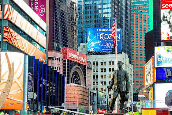 Kaupungin aukio, jossa värikkäitä kyltejä, mainoksia ja patsas etualalla. (Tekoälyn luoma teksti)