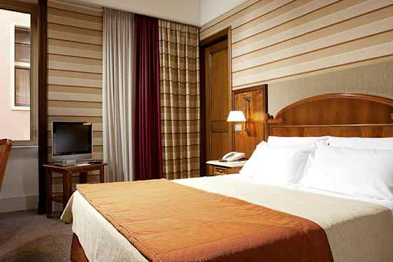 Hotellihuone, jossa on parivuode, työpöytä televisiolla ja ikkuna. (Tekoälyn luoma teksti)