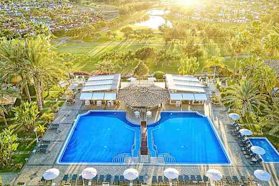 Kuva kahdesta suuresta altaasta lomakohteessa, ympärillä palmuja ja aurinkotuoleja. (Tekoälyn luoma teksti)