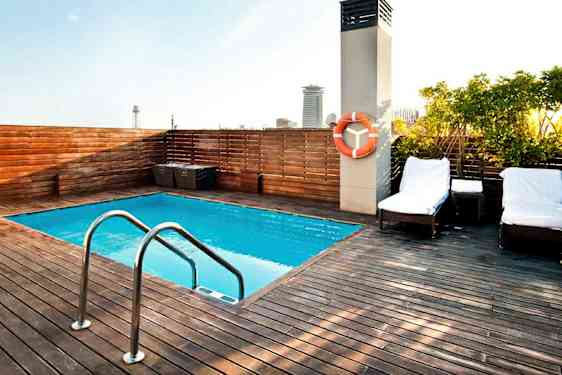 Kattoterassi, jossa on pieni uima-allas, puulattiapinta ja aurinkotuoleja. (Tekoälyn luoma teksti)