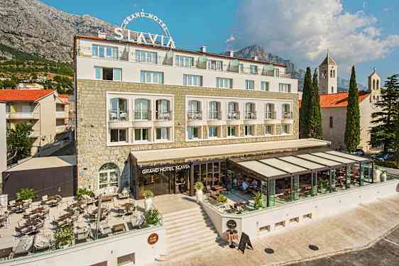 Grand Hotel Slavian kuva, jossa on ulkoterassi ja lasitettu ravintolaosio. (Tekoälyn luoma teksti)