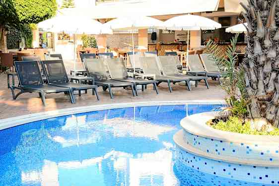 Aurinkotuoleja uima-altaan reunalla, taustalla aurinkovarjoja. (Tekoälyn luoma teksti)