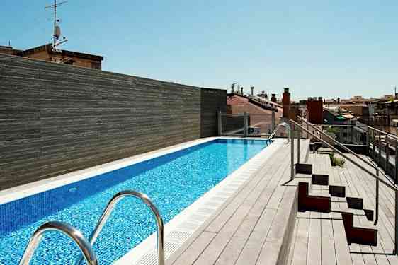 Kattoterassi, jossa on pitkä uima-allas, jota ympäröi terassilattia ja vieressä istuimia. (Tekoälyn luoma teksti)