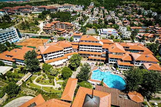 Ilmakuva lomakohteesta, jossa on punaisia kattoja, uima-allas ja ympäröiviä viheralueita. (Tekoälyn luoma teksti)