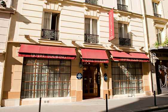 Hotel Touringin julkisivu punaisilla markiiseilla ja lasiovisisäänkäynnillä. (Tekoälyn luoma teksti)