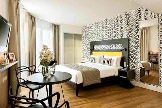 Moderni hotellihuone, jossa on parivuode, värikäs tapetti ja istuinryhmä. (Tekoälyn luoma teksti)