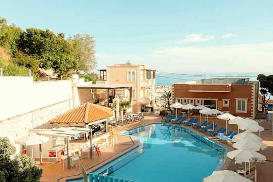 Hotellin uima-allas, jonka vieressä aurinkotuoleja ja varjoja, taustalla rakennuksia ja kasvillisuutta. (Tekoälyn luoma teksti)