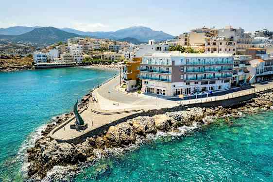 Rannikko, jossa rakennuksia meren rannalla, kirkas vesi ja kivinen ranta. (Tekoälyn luoma teksti)