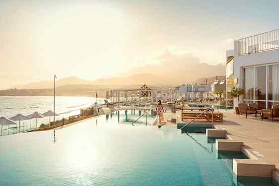 Nainen infinity-altaan vieressä, taustalla meri ja vuoristo. (Tekoälyn luoma teksti)