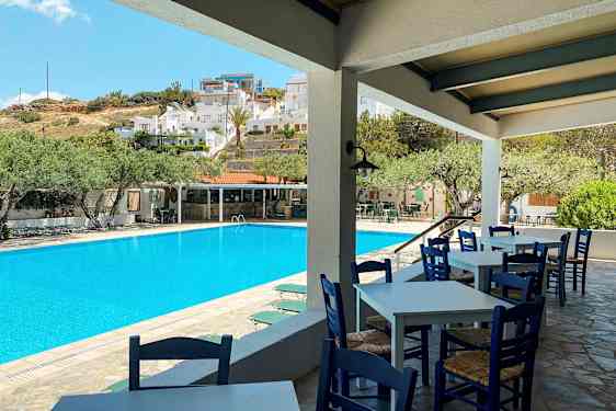 Ulkoallas, jonka etualalla on tuoleja ja pöytiä, taustalla rakennuksia. (Tekoälyn luoma teksti)