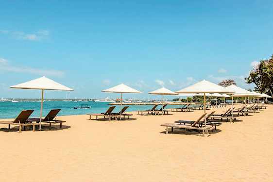 Ranta aurinkotuoleilla, jotka ovat aurinkovarjojen alla meren äärellä. (Tekoälyn luoma teksti)