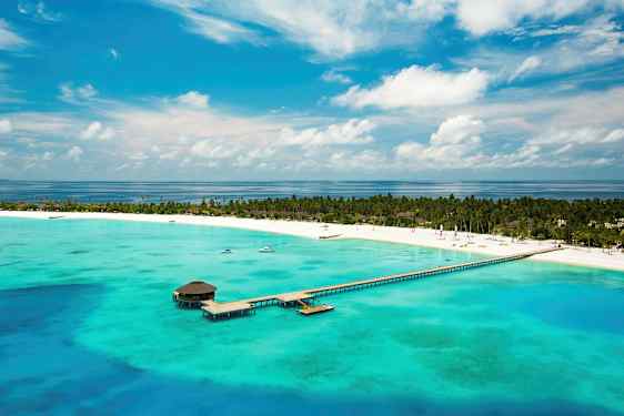 Ilmakuva trooppisesta rannasta, jossa on laituri, joka ulottuu turkoosiin veteen. (Tekoälyn luoma teksti)