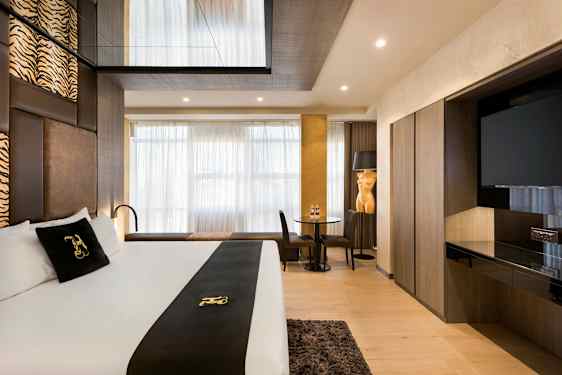 Moderni hotellihuone, jossa on parivuode, istuma-alue ja televisio. (Tekoälyn luoma teksti)