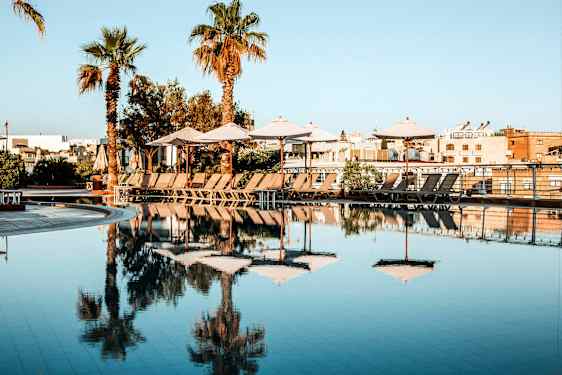 Uima-allas, jossa aurinkovarjoja ja lepotuoleja aurinkoisena päivänä. (Tekoälyn luoma teksti)