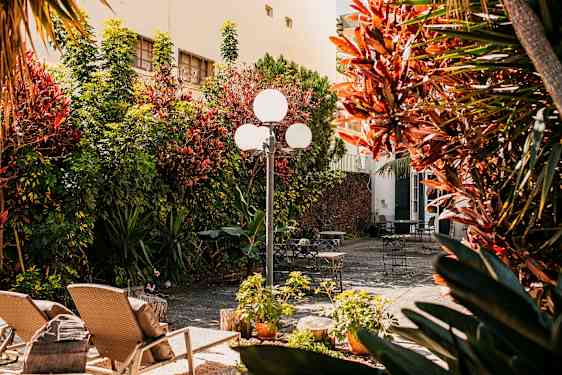 Aurinkoinen sisäpiha, jossa on puutarhakalusteita ja kasveja. (Tekoälyn luoma teksti)