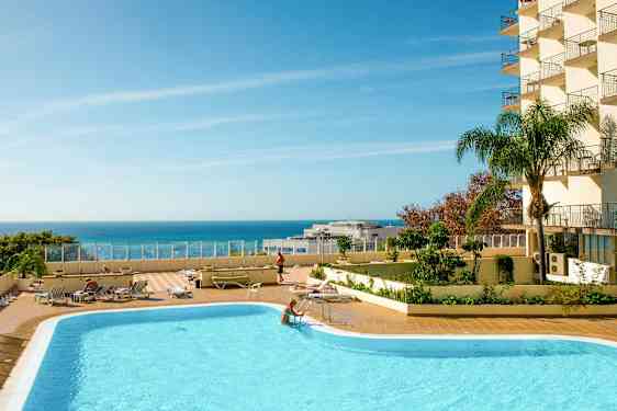 Ulkouima-allas aurinkotuoleineen ja kirkkaan sininen taivas meren yllä. (Tekoälyn luoma teksti)