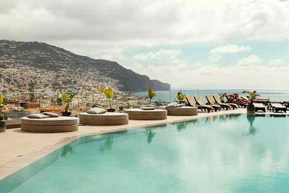 Infinity-allas, jossa aurinkotuoleja ja näkymä kaupunkiin ja vuorille. (Tekoälyn luoma teksti)