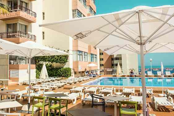 Ulkouima-allasalue, jossa on aurinkotuoleja ja aurinkovarjoja hotellin yhteydessä. (Tekoälyn luoma teksti)