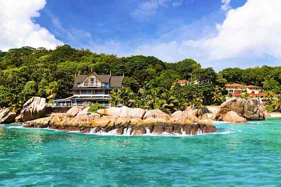 Ranta kallioineen rakennuksen edessä, jota ympäröi vehreys. (Tekoälyn luoma teksti)