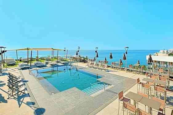 Ulkouima-allas, jossa aurinkotuoleja ja varjoja sekä näkymä merelle. (Tekoälyn luoma teksti)