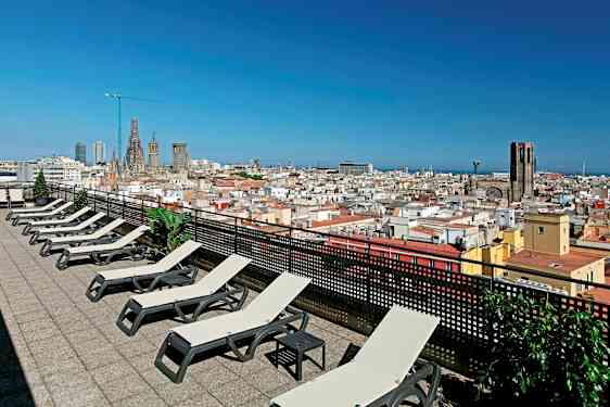 Kattoterassi aurinkotuoleilla ja näkymä kaupunkiin, jossa on kirkko ja sininen taivas. (Tekoälyn luoma teksti)