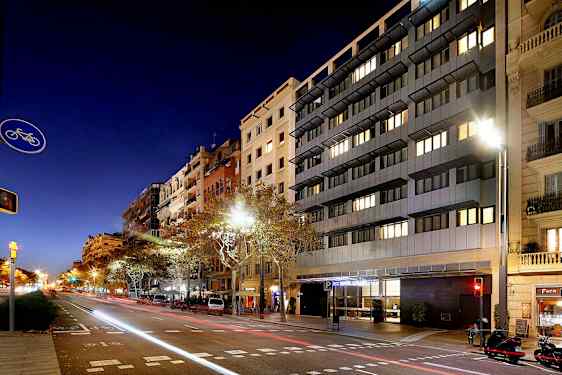 Katu kaupunkimaisemassa yöllä, korkeat rakennukset ja autoja tien varrella. (Tekoälyn luoma teksti)