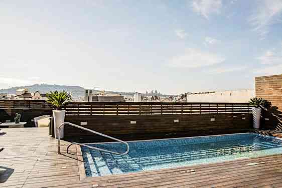 Kattoterassi, jossa on uima-allas, puupaneelien ympäröimä ja näkymä kaupunkiin. (Tekoälyn luoma teksti)