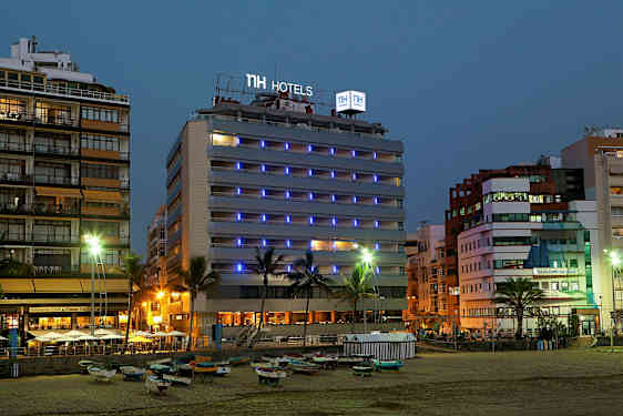 Kuva hotellista meren rannalla illalla, valokyltit ja ympäröivät rakennukset näkyvät. (Tekoälyn luoma teksti)