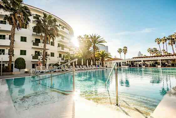 Ulkoallas hotellin edessä, ympärillä palmuja ja aurinkotuoleja. (Tekoälyn luoma teksti)