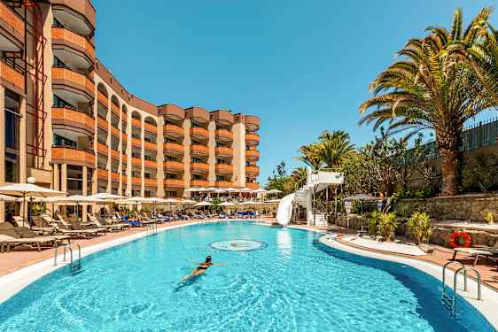 Uima-allas, jossa nainen ui, ympärillä lepotuoleja ja hotelli taustalla. (Tekoälyn luoma teksti)