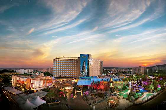 Näkymä lomahotelliin ja värikkääseen teemapuistoon auringonlaskun edessä. (Tekoälyn luoma teksti)