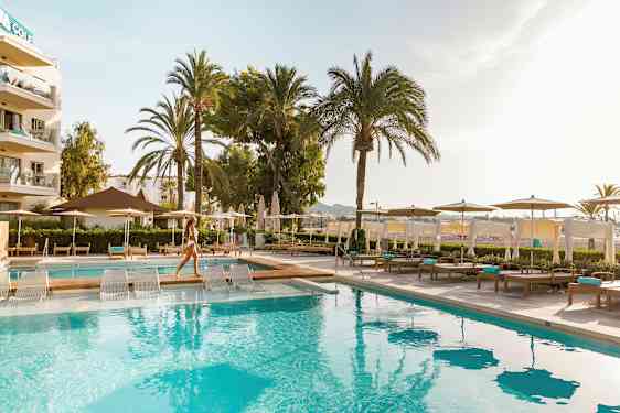 Uima-allas, jossa on aurinkotuoleja ja aurinkovarjoja hotellialueella. (Tekoälyn luoma teksti)