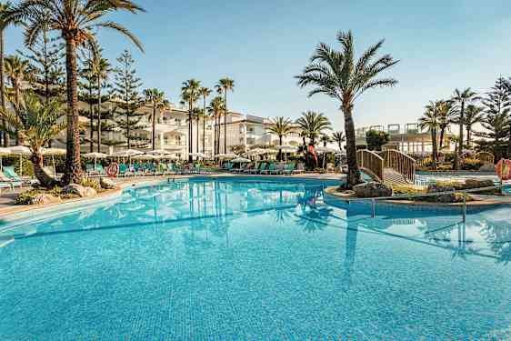 Ulkouima-allas, jota ympäröivät aurinkotuolit, varjot ja palmut hotellin luona. (Tekoälyn luoma teksti)