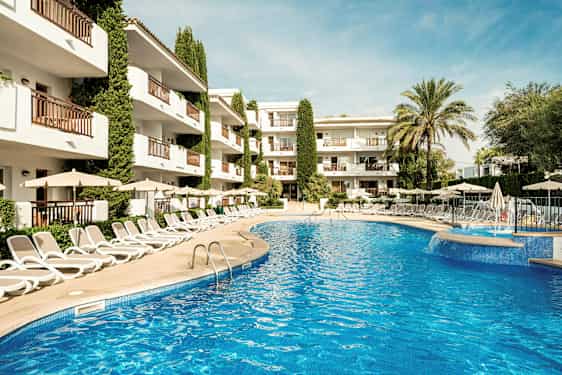 Kuva ulkouima-altaasta, joka on ympäröity aurinkotuoleilla ja sateenvarjoilla, taustalla hotelli. (Tekoälyn luoma teksti)