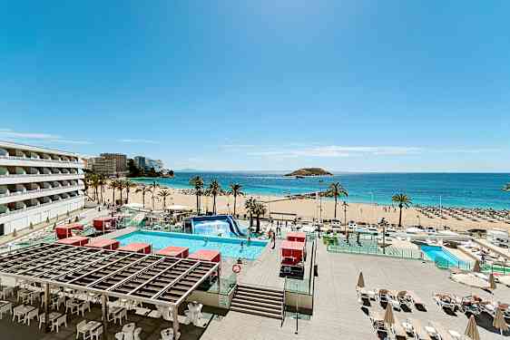 Kuva aurinkoisesta rannasta, palmupuista, turkoosista vedestä ja etualan uima-altaasta. Rakennuksia näkyy vasemmalla. (Tekoälyn luoma teksti)