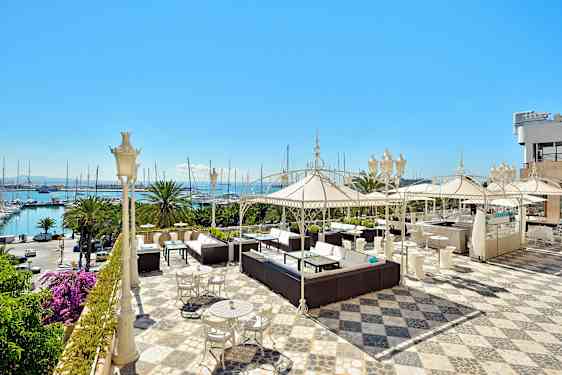 Tilava terassi, jossa on istuinryhmiä, aurinkovarjoja ja näkymä merelle. (Tekoälyn luoma teksti)