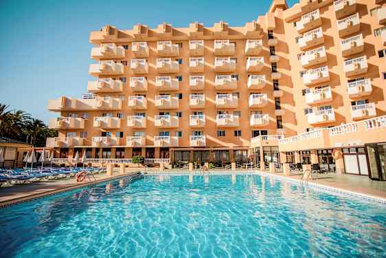 Rakennus, jossa on useita parvekkeita, ja sen edustalla suuri uima-allas. (Tekoälyn luoma teksti)