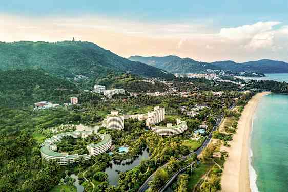 Ilmakuva rannikkoalueesta, jossa on hotellirakennuksia, ympäröivää vihreää ja ranta. (Tekoälyn luoma teksti)