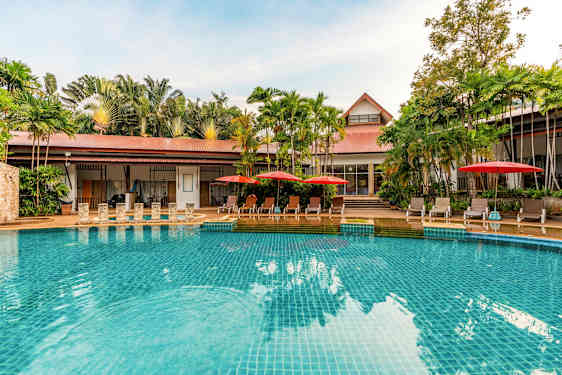 Uima-allas, jossa kirkkaan sinistä vettä, ympärillä aurinkotuoleja punaisilla varjoilla ja taustalla vihreitä palmuja. (Tekoälyn luoma teksti)