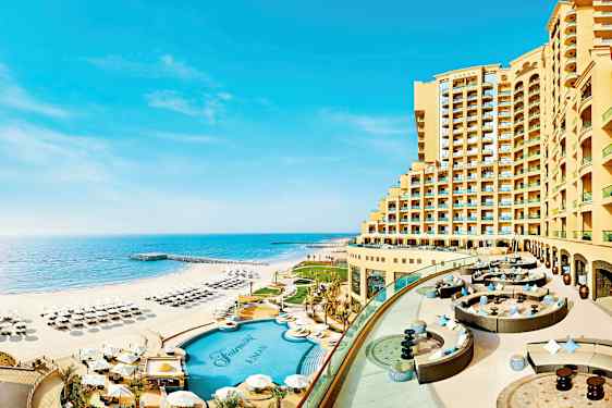 Hotelli, joka sijaitsee hiekkarannan vieressä, jossa on uima-allas ja aurinkotuoleja rannalla. (Tekoälyn luoma teksti)