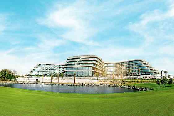 Moderni hotelli, jossa on monikerroksisia rakennuksia, joita ympäröivät viheralueet ja lampi. (Tekoälyn luoma teksti)