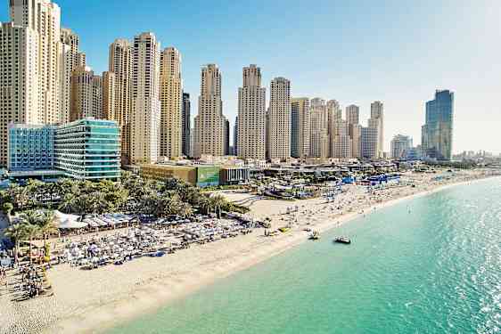 Ranta, jossa ihmiset nauttivat auringosta, taustalla korkeat pilvenpiirtäjät ja kirkkaan turkoosi vesi. (Tekoälyn luoma teksti)