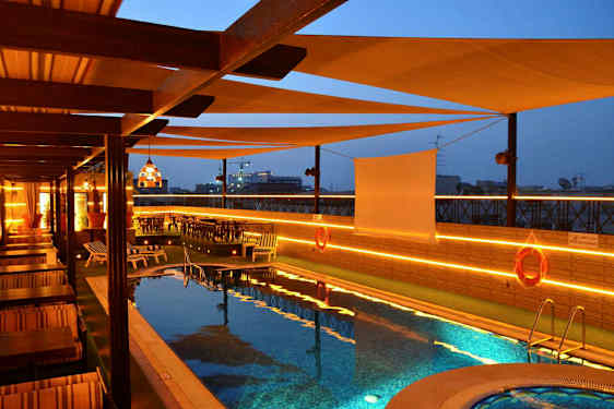 Uima-allas terassilla, jossa on aurinkotuoleja ja pöytiä, valaistus iltaisin. (Tekoälyn luoma teksti)