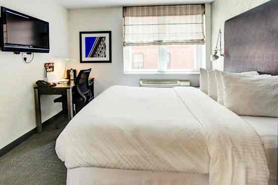 Makuuhuone, jossa on parivuode, työpöytä, tuoli ja seinälle kiinnitetty televisio. (Tekoälyn luoma teksti)