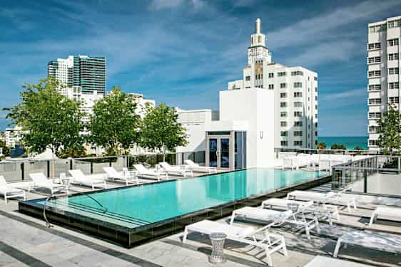 Kattouima-allas, jonka ympärillä on aurinkotuoleja, ympäröitynä moderneilla rakennuksilla ja vehreydellä. (Tekoälyn luoma teksti)