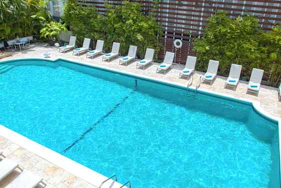 Ulkouima-allas, jonka ympärillä aurinkotuoleja ja viheralueita taustalla. (Tekoälyn luoma teksti)